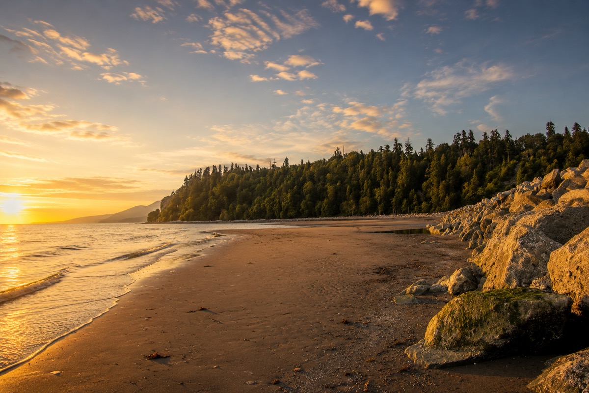 Golden-hour sunset over the sand and Pacific surf at Wreck Beach, Vancouver